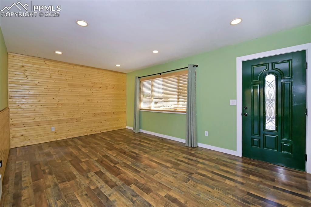 Image 9 of 39: Entryway with wooden walls, dark wood finished floors, and recessed lightin