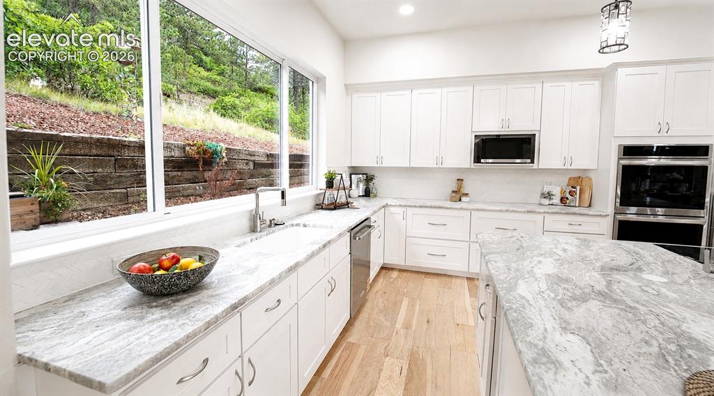 Image 14 of 49: Light and bright Gourmet Kitchen with wall of windows, white cabinetry and