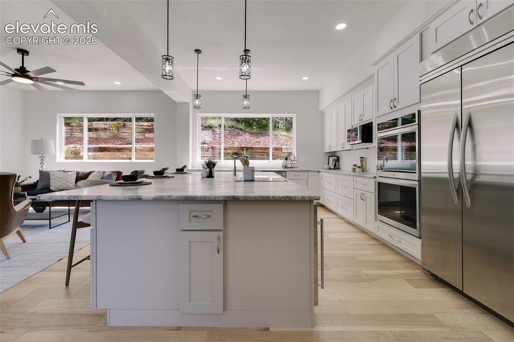 Image 17 of 49: Expanded Island with leathered granite countertop, pendant lighting, and br