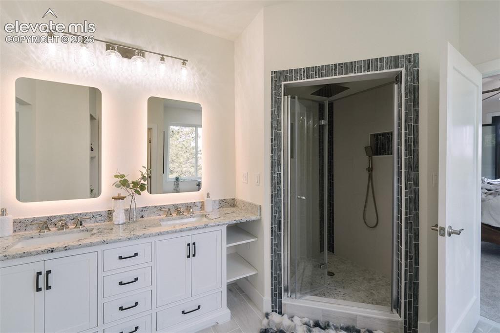 Image 34 of 49: Vanity and tiled walk in shower with rain shower head and interior light in