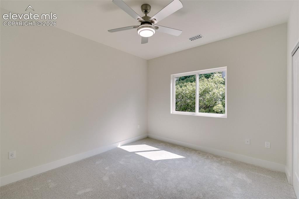 Image 36 of 49: Upper Level Bedroom #5 with neutral carpet and a lighted ceiling fan.