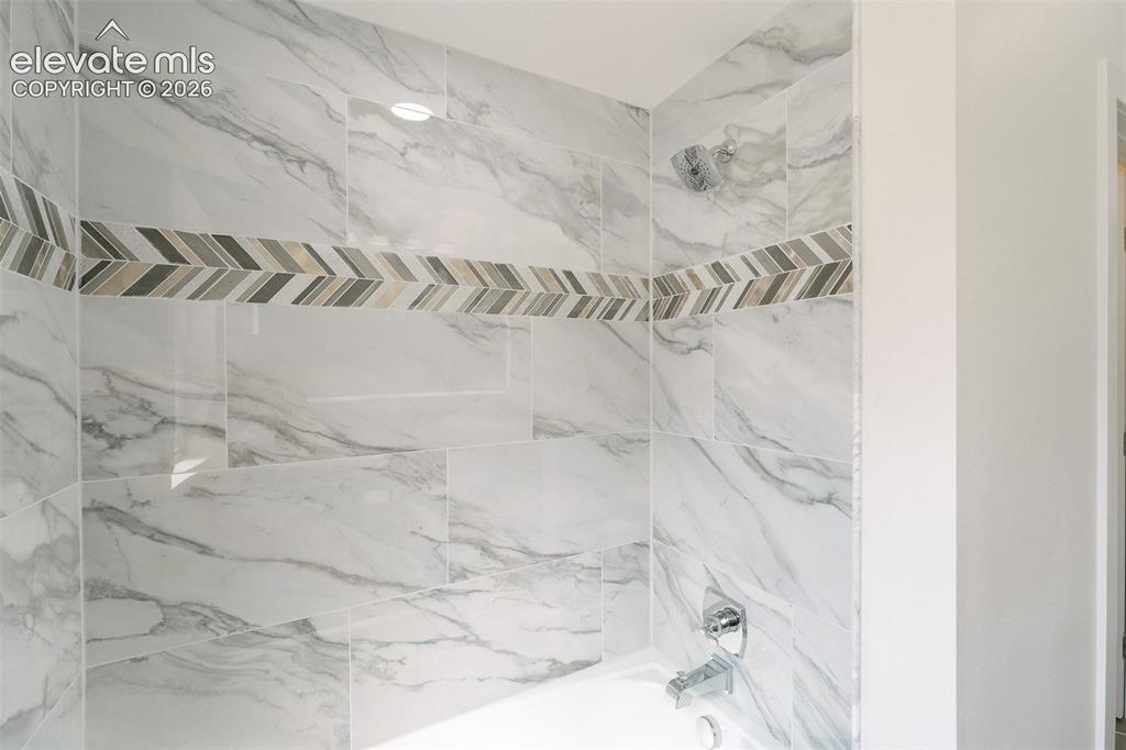 Image 38 of 49: Tiled tub/shower in the upper level Full Bathroom.