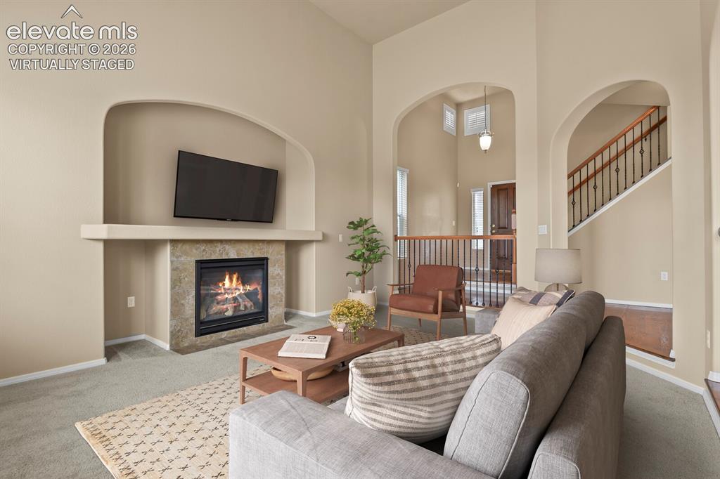 Image 11 of 50: **Virtually Staged** Living room featuring a gas fireplace with a stone sur