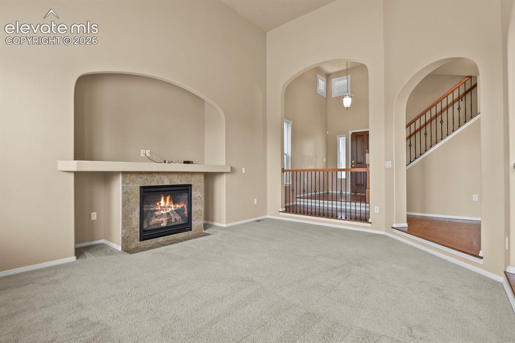 Image 12 of 50: Arched doorways, a gas fireplace with a tiled surround, a built-in media ni