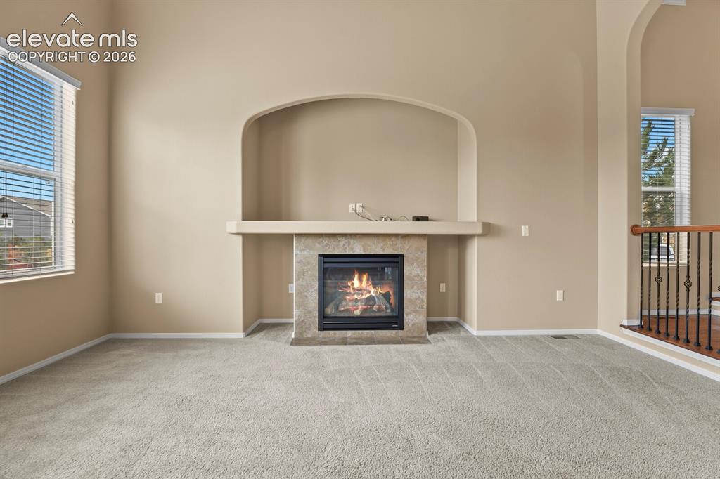 Image 13 of 50: Recessed fireplace with a tile surround and mantel, arched wall niche, neut