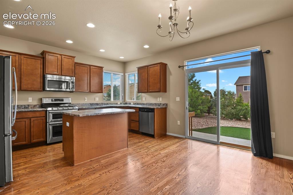 Image 14 of 50: Wood-finish flooring throughout, complemented by a kitchen island with ston