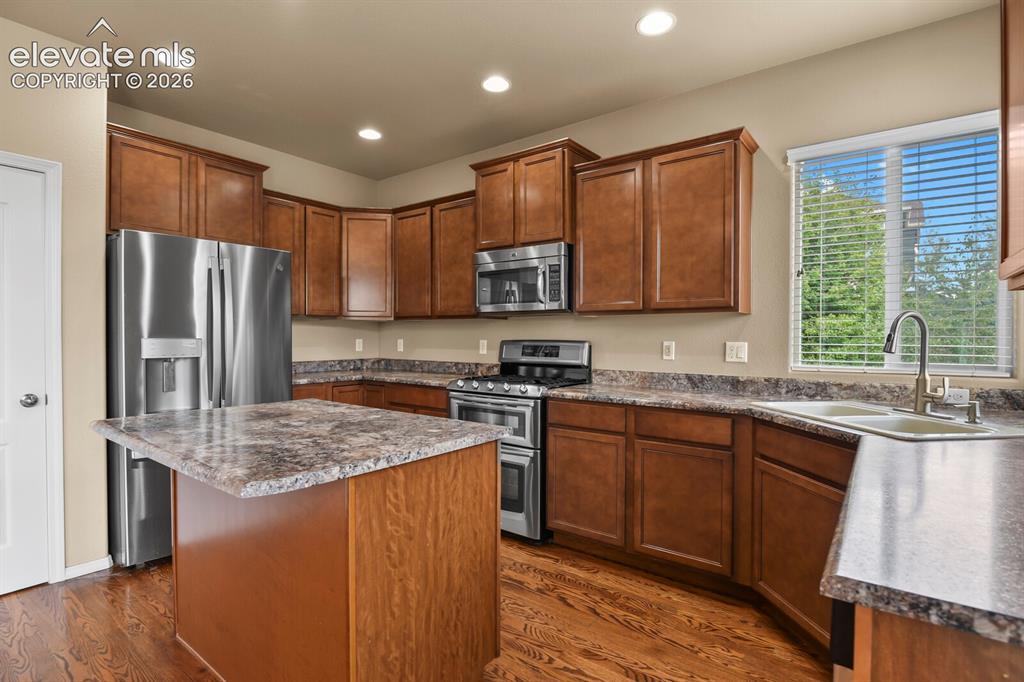 Image 17 of 50: Kitchen featuring rich wood cabinetry, stainless steel appliances, a center
