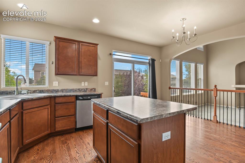 Image 19 of 50: Kitchen featuring wood-finish flooring, dark wood cabinetry, and stone-fini