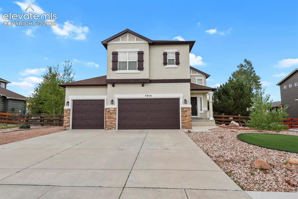Image 2 of 50: Stucco exterior with stone accents, featuring a two-car garage, concrete dr