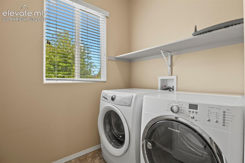 Image 21 of 50: Window with white blinds, neutral wall tones, and overhead shelving