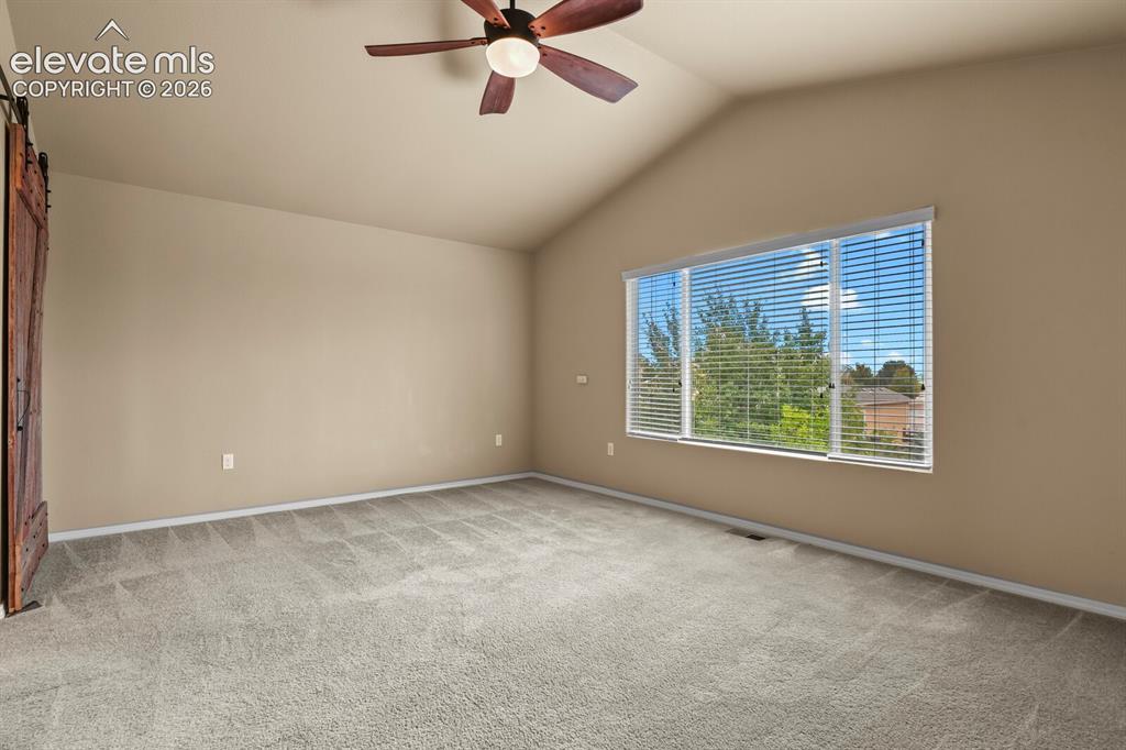 Image 23 of 50: Vaulted ceiling with a ceiling fan, large window with blinds, and light-ton