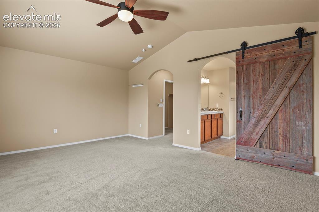 Image 25 of 50: Vaulted ceiling with a ceiling fan, carpeted flooring, and a rustic wood sl