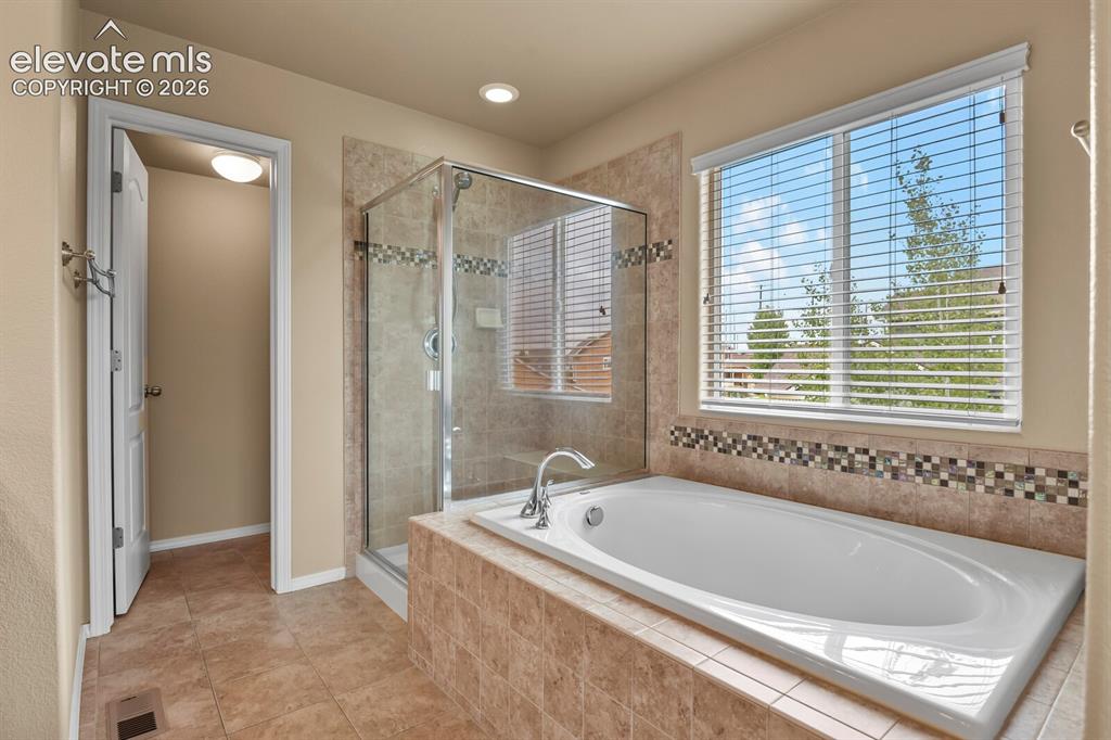 Image 27 of 50: Built-in soaking tub, separate glass-enclosed shower, large window with bli