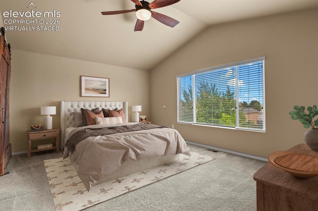 Image 28 of 50: **Virtually Staged** Vaulted ceiling with a ceiling fan, broad window with