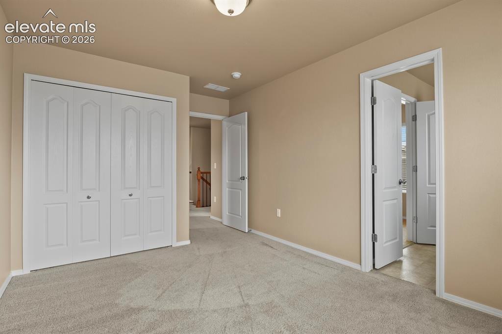 Image 30 of 50: Neutral tone wall paint, light gray carpet flooring, white bi-fold closet d