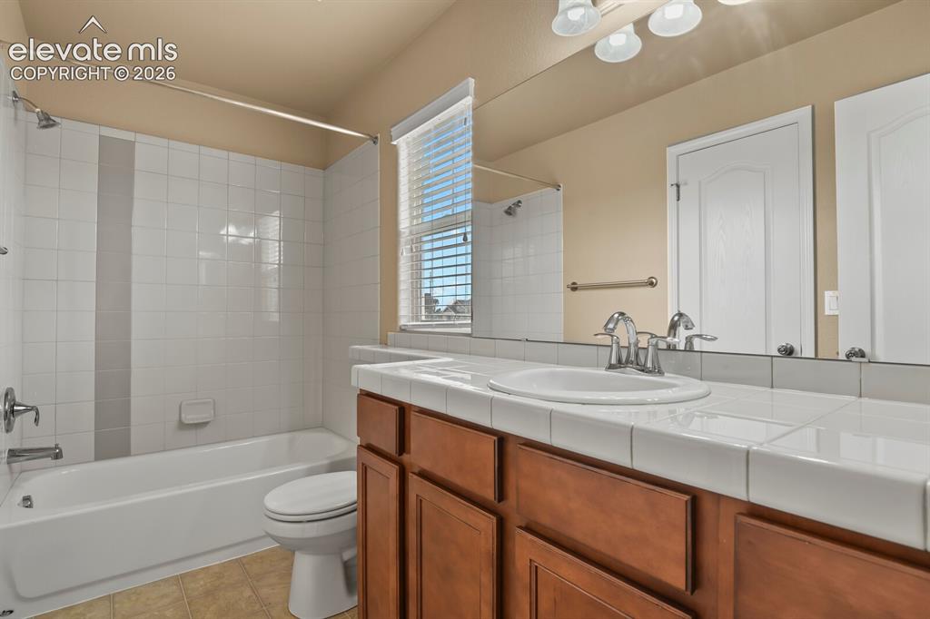Image 31 of 50: Full vanity mirror, integrated vanity lighting, tile countertop with underm