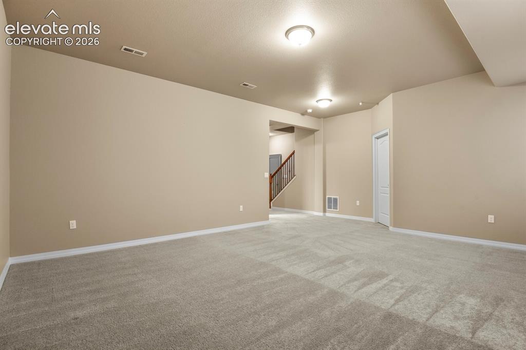 Image 38 of 50: Spacious interior featuring light-toned walls, neutral carpeting, and overh