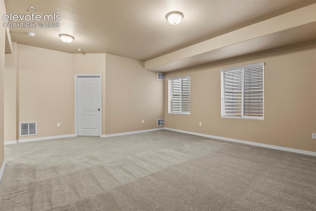 Image 39 of 50: Spacious interior with neutral carpeting, recessed ceiling lighting, and mu