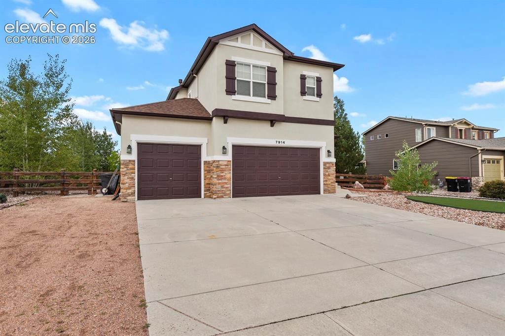 Image 4 of 50: Stucco exterior with stone accents and two-car garage