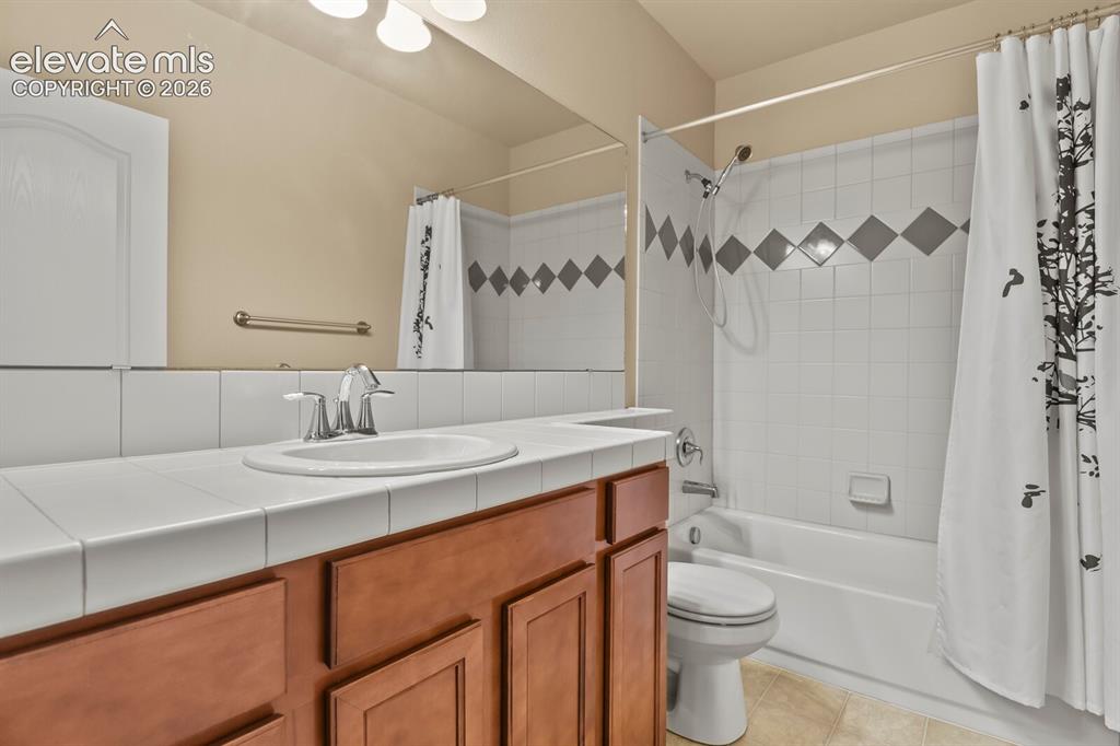 Image 40 of 50: Vanity with a tiled countertop and integrated sink, chrome faucet, wood-fin
