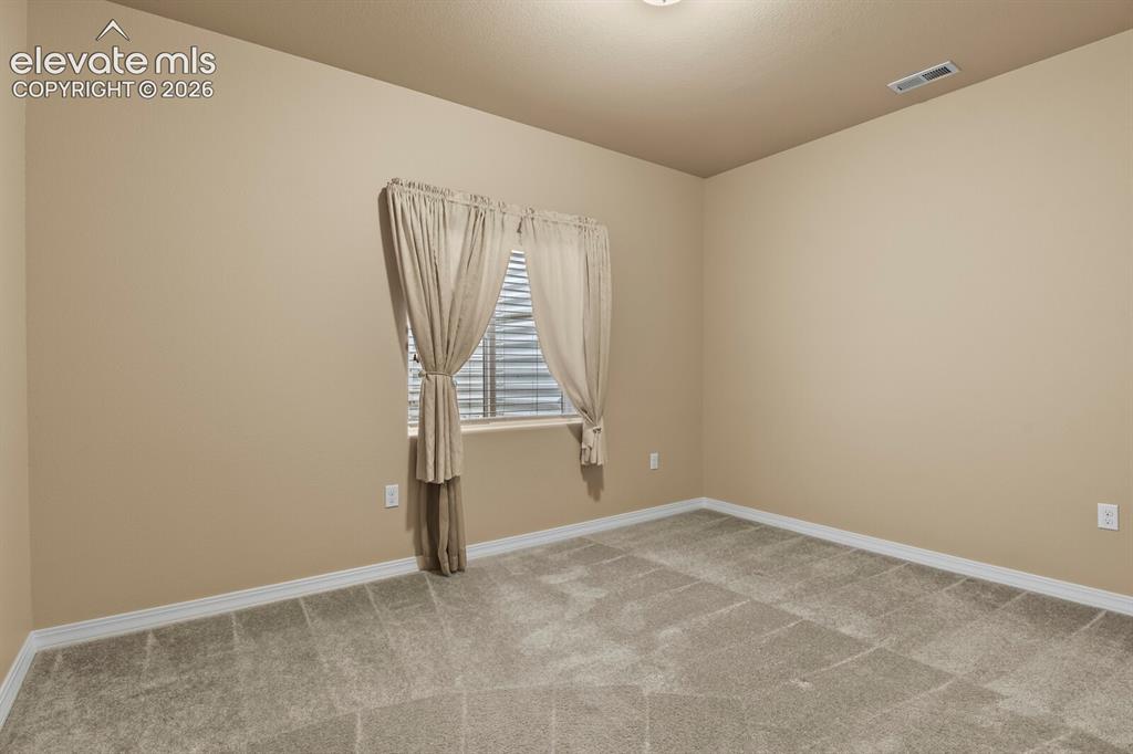 Image 41 of 50: Neutral tone walls, grey carpeting, and a window with horizontal blinds