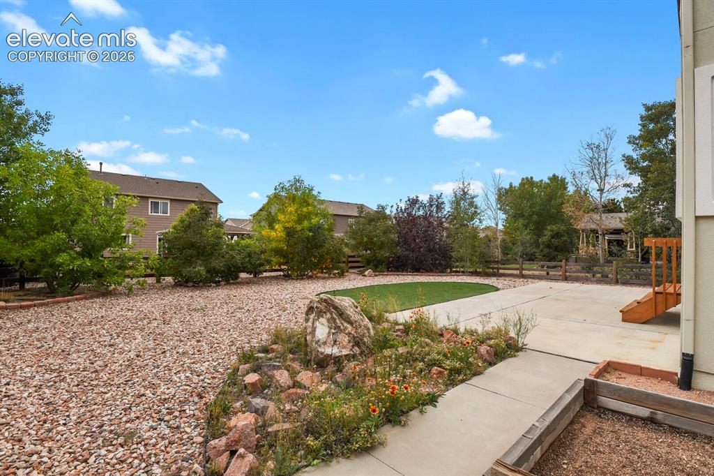 Image 43 of 50: Expansive outdoor area featuring a concrete patio, stepping stones, and a r
