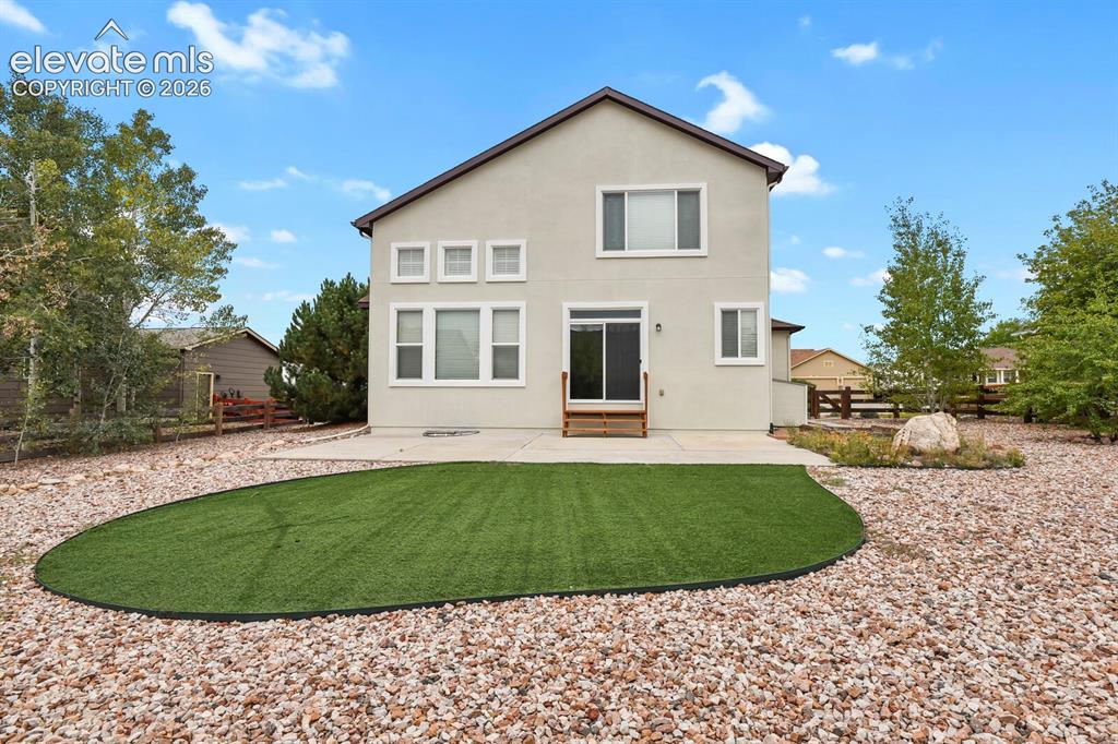 Image 45 of 50: Rear elevation featuring a concrete patio, sliding glass door, and a low-ma