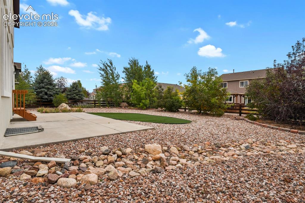 Image 47 of 50: Expansive backyard featuring a concrete patio, artificial turf area, decora