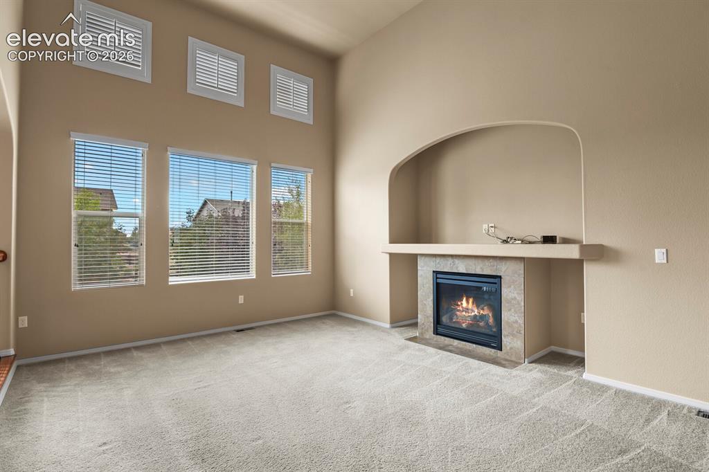 Image 8 of 50: Vaulted ceilings with upper transom windows, a tiled fireplace with mantel,
