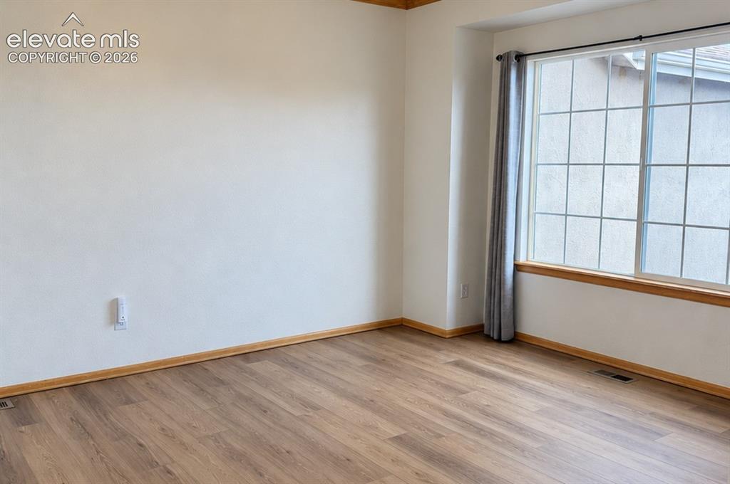 Image 11 of 48: Wood-finish flooring with coordinating wood trim, large window with grid pa