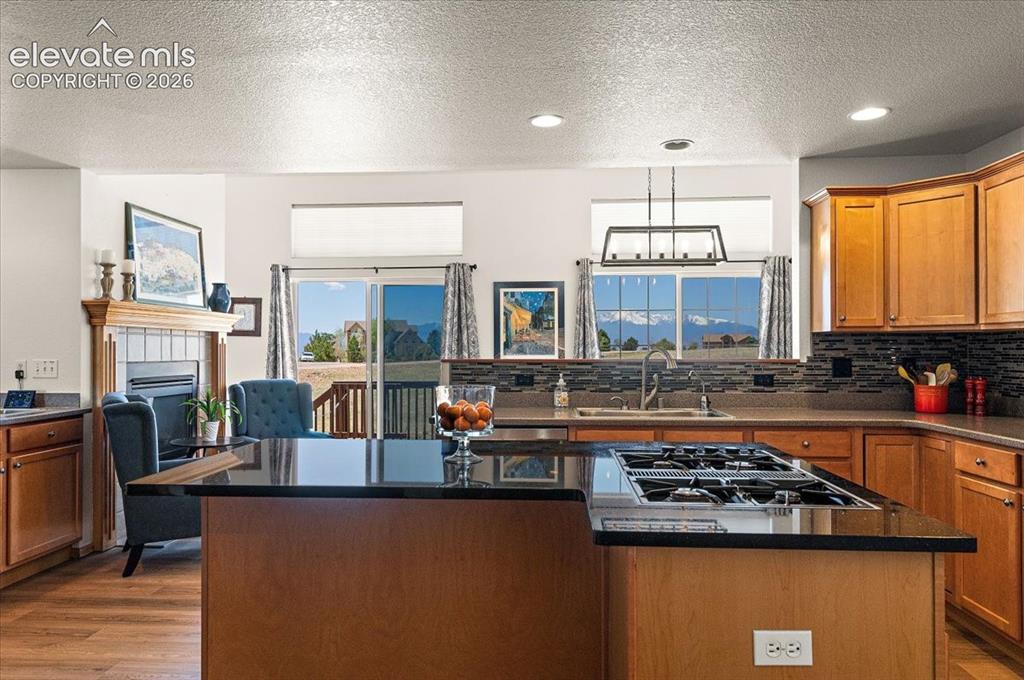 Image 12 of 47: Kitchen featuring a gas cooktop island, light wood-finish cabinetry, a tile