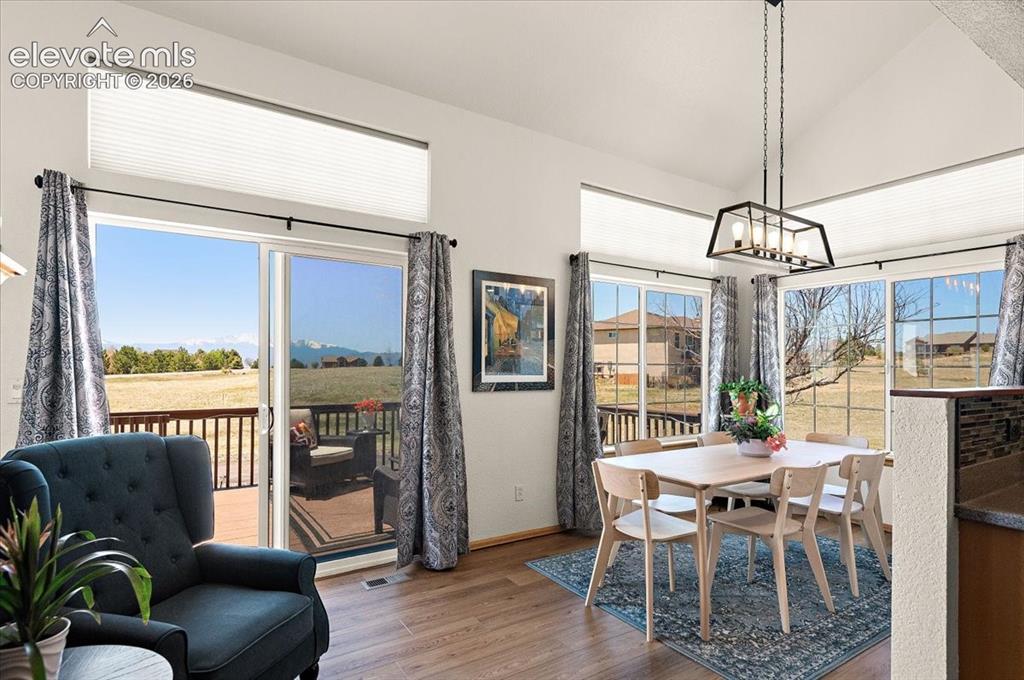 Image 14 of 47: Vaulted ceiling dining area featuring wood-finish flooring and ample natura