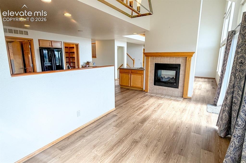 Image 14 of 48: Wood-finish flooring, recessed lighting, gas fireplace with tile surround a