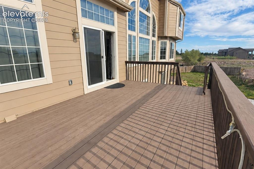 Image 16 of 48: Expansive outdoor deck with decking, a durable railing system, and a slidin