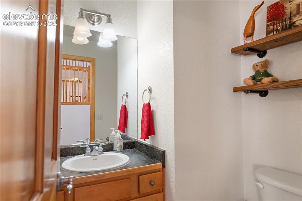 Image 17 of 47: 1/2 Bath vanity with wood-finish cabinetry, a dark countertop, and an under