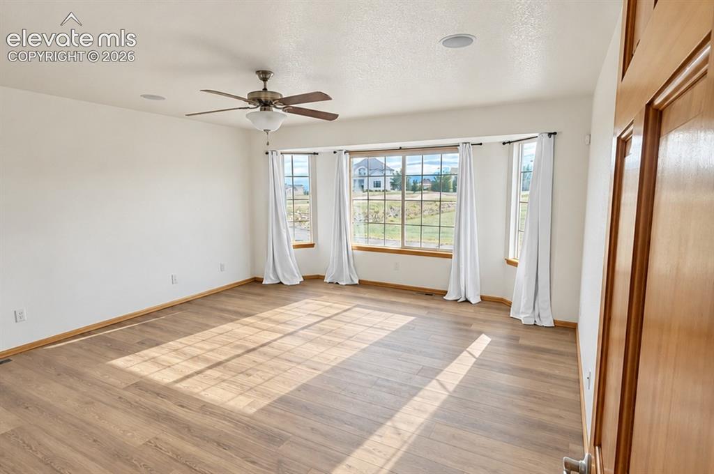Image 18 of 48: Main-level primary. Spacious room featuring wood-finish flooring, a multi-p