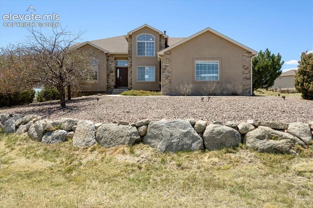 Image 2 of 47: Stucco exterior with stone accents and a prominent arched window on the upp