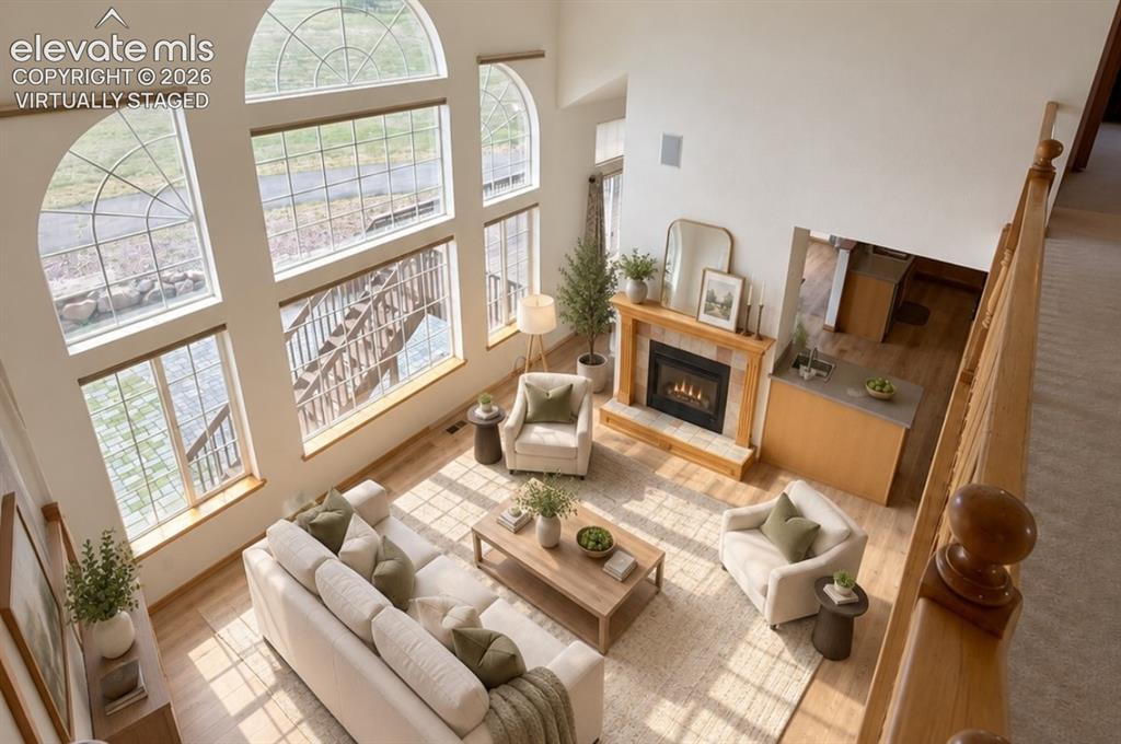 Image 20 of 48: Two-story living area with expansive arched windows, a gas fireplace with a