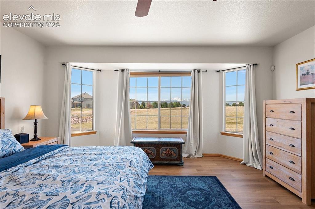 Image 22 of 47: Spacious room featuring wood-finish flooring, a ceiling fan, and a wide bay