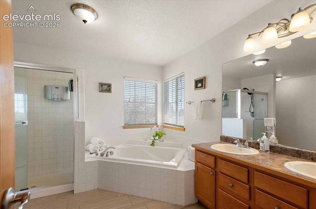Image 23 of 47: Bathroom featuring a soaking tub with tiled surround, a glass-enclosed show