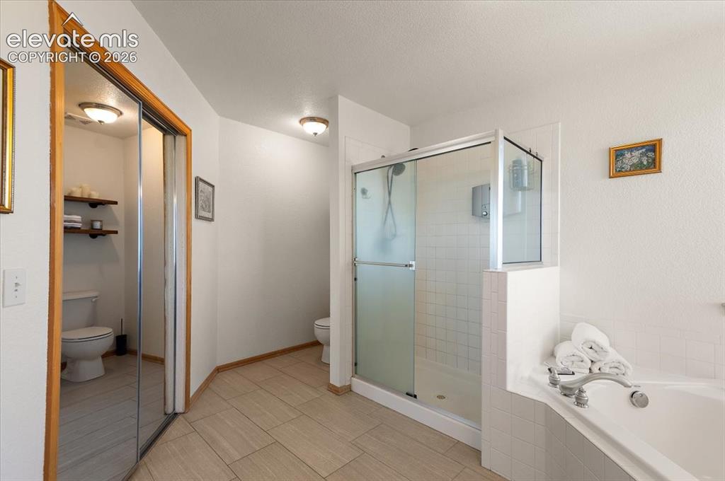 Image 24 of 47: Bathroom featuring a corner soaking tub, a glass-enclosed shower with tiled