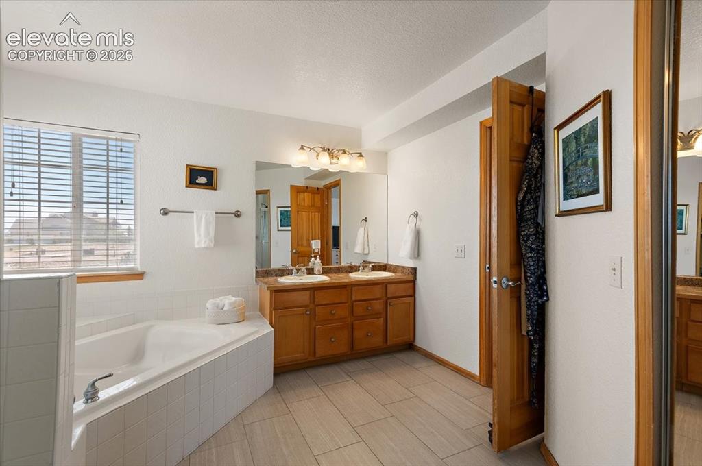 Image 25 of 47: Bathroom featuring a built-in corner soaking tub with tile surround, a doub