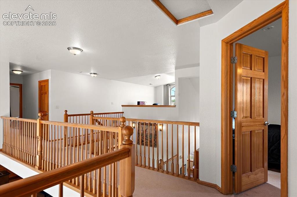 Image 26 of 47: Upper-level landing featuring wood balusters and railings, a paneled wood d