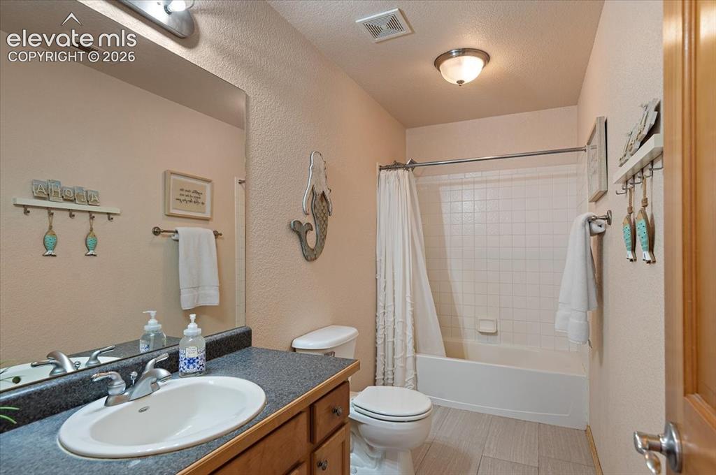 Image 31 of 47: Bathroom featuring a single vanity with an integrated sink, dark countertop