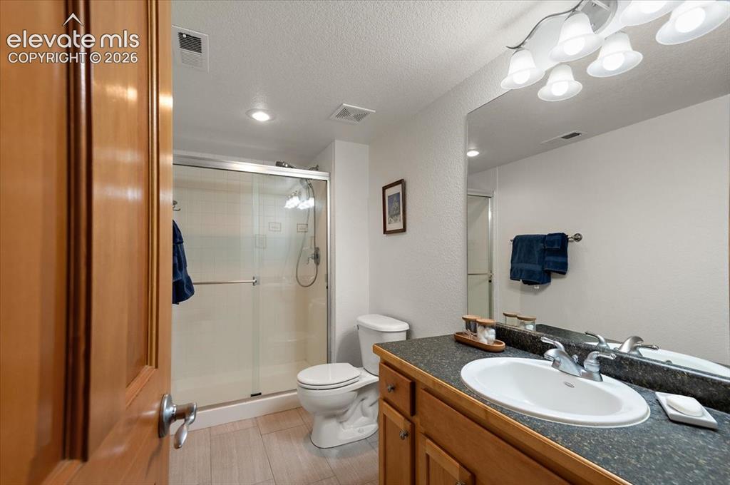 Image 38 of 47: Bathroom featuring a wood-finish vanity with an integrated sink, a dark cou