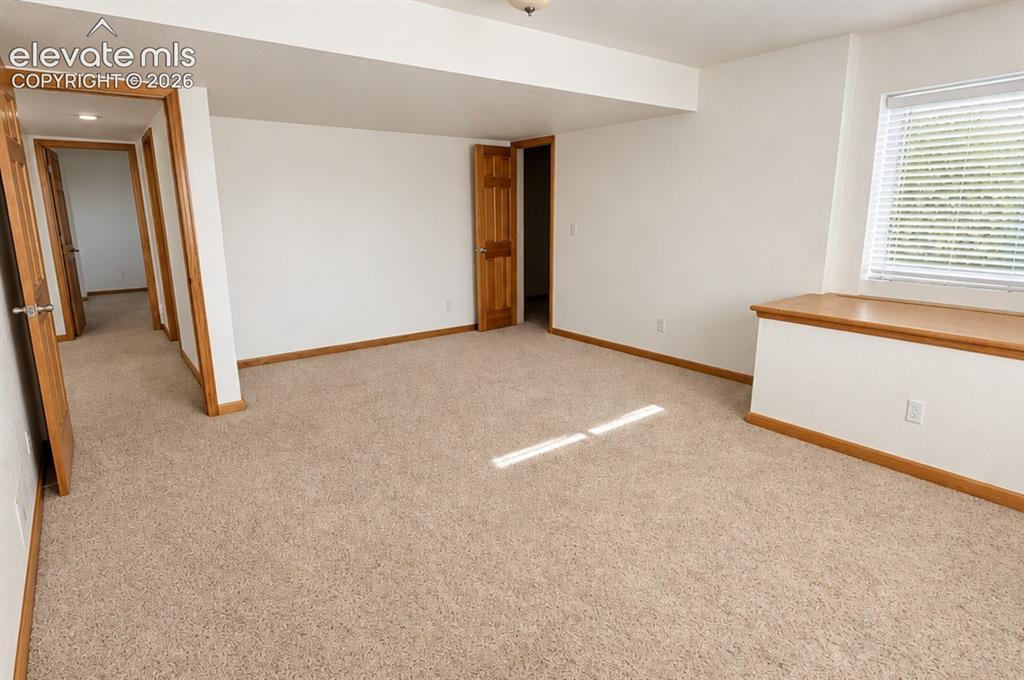 Image 39 of 48: Basement bedroom 2/2 or workout area. Neutral tone carpeting with white wal
