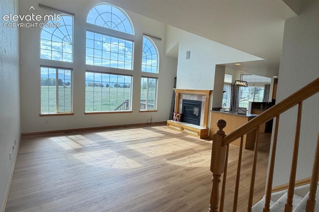 Image 46 of 48: Soaring ceilings with arch-top windows, wood-finish flooring, and a firepla