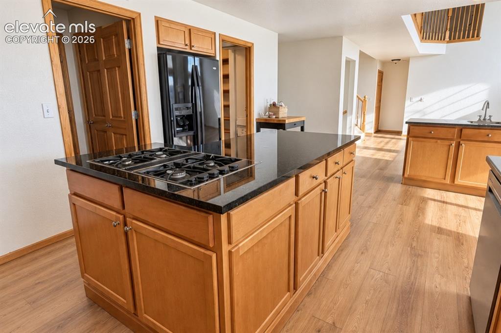 Image 47 of 48: Kitchen island with a built-in gas cooktop, granite countertop, and wood-fi