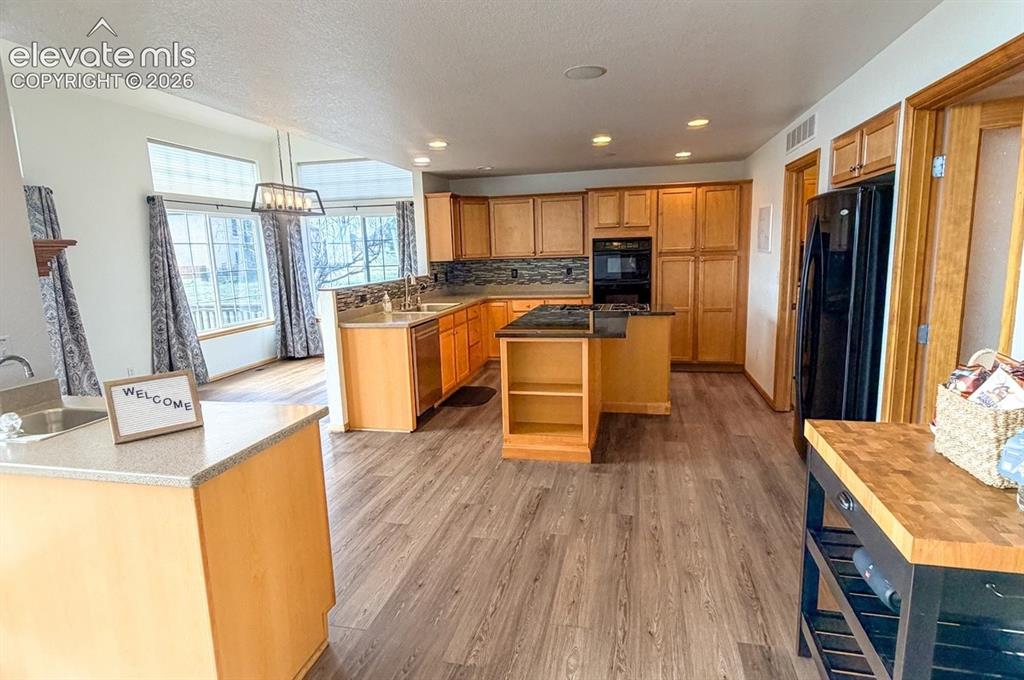 Image 48 of 48: Open-concept kitchen with wood-finish flooring, light wood cabinetry, a cen