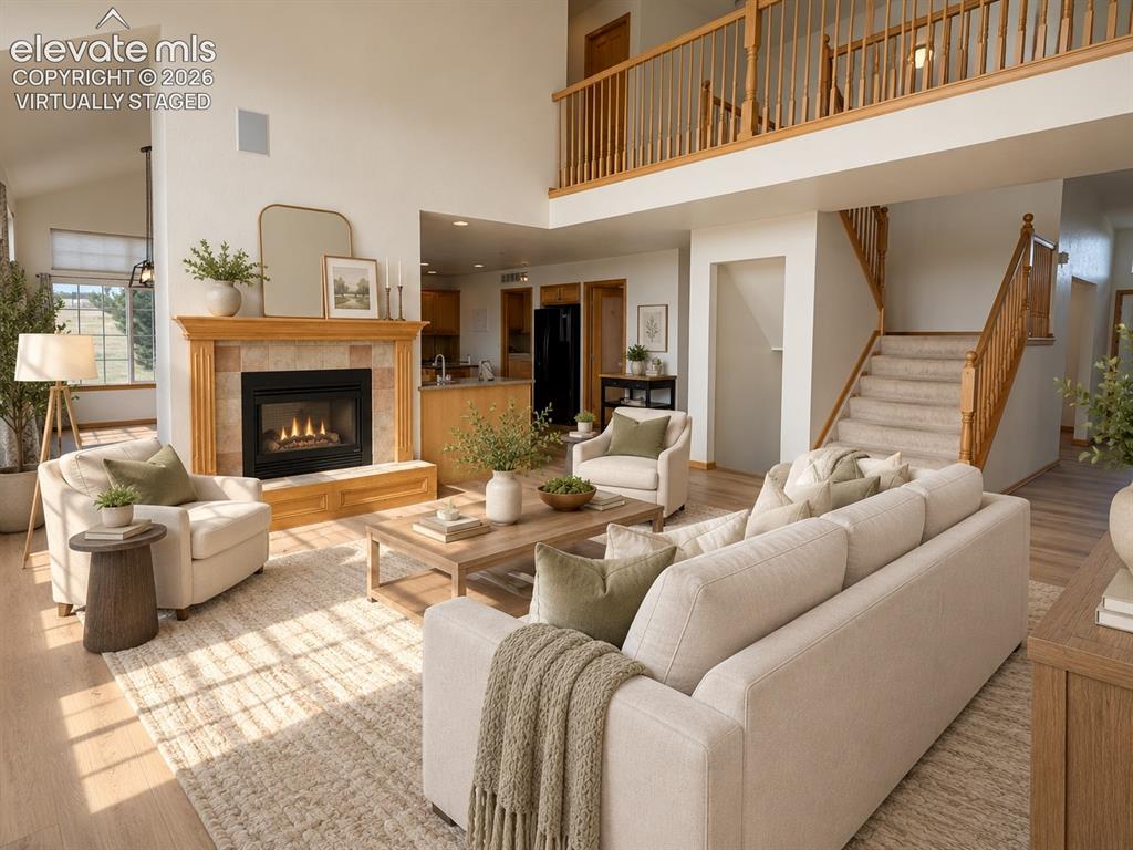Image 5 of 48: Two-story living area with a gas fireplace, a wood mantel, and tile surroun